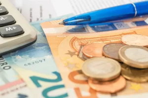banconote e monete vicino ad una penna e ad una calcolatrice
