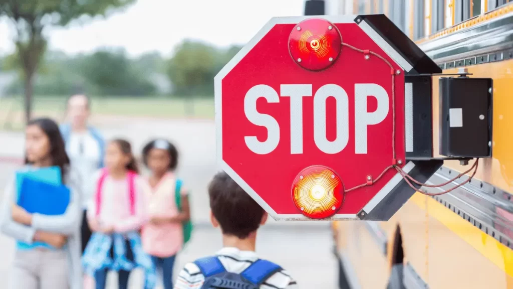 bambini scendono dallo scuola bus con la scritta stop