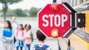 bambini scendono dallo scuola bus con la scritta stop