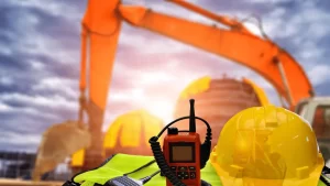 gilet di sicurezza, casco e ricetrasmittente con sullo sfondo una gru