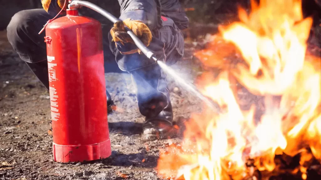 Addetto antincendio con un estintore cerca di domare un piccolo incendio