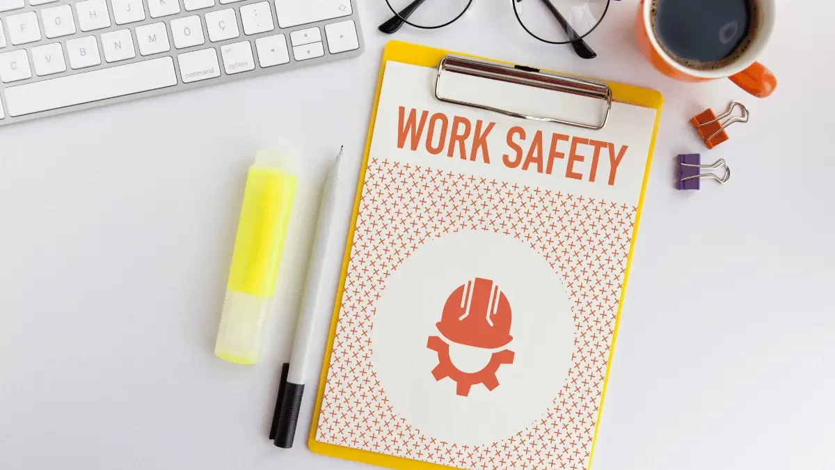 una tastiera di computer con vicino una cartella con la scritta "Work safety"