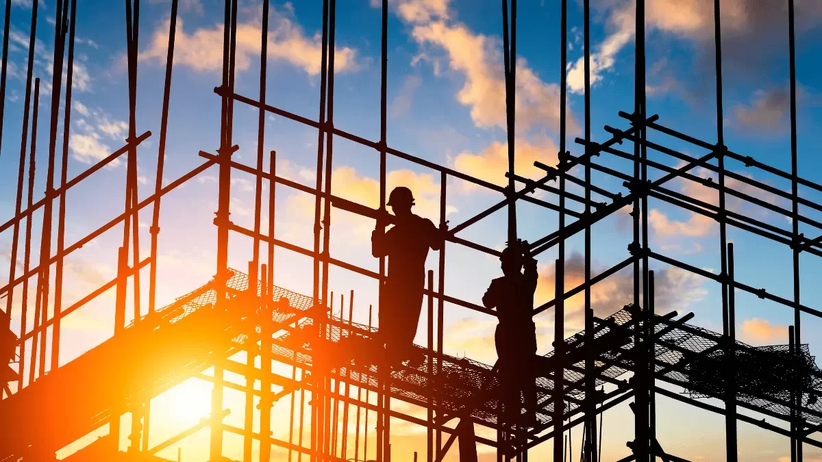 lavoratori su un impalcatura con il tramonto sullo sfondo